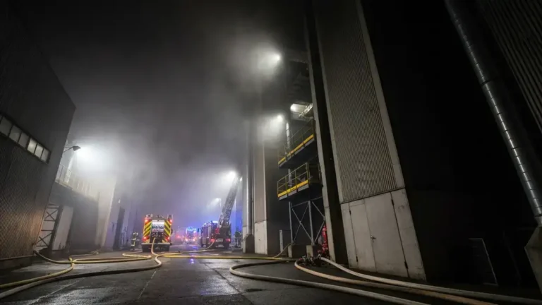 Industrial moulding facility at night with emergency response lighting after an Ohio woodworking sawdust explosion.