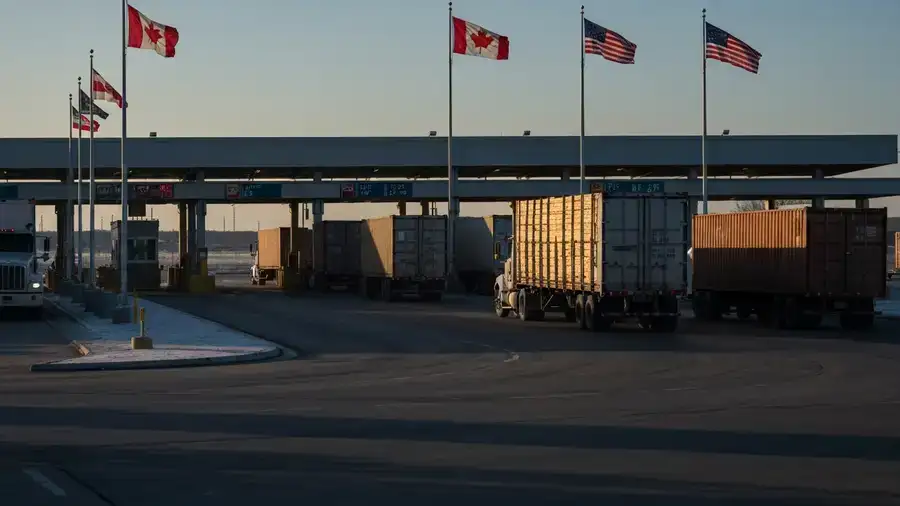 Lumber trucks queued at a Canada-US border crossing affected by Section 338 tariffs